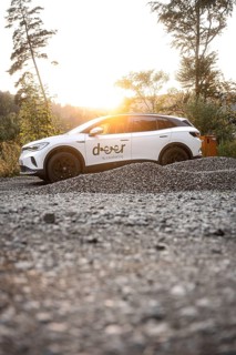 White car at sunset on gravel surrounded by nature, peaceful atmosphere, VW ID4 electric car, deer