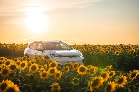 A white car is parked in a sunflower field at sunset, VW ID4 electric car, Deer Carsharing, Calw,
