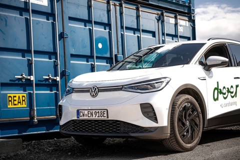 White car in an urban location next to a blue container, industrial atmosphere, VW ID4 electric