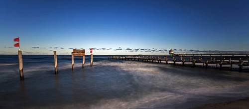 Wooden sign in the sea with inscription Zingst and Holzsteg, panorama, long exposure, evening