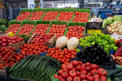 A large market stand full of tomatoes and fresh vegetables in green boxes, Akhaltsikhe market,