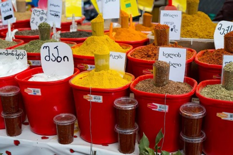A colorful market stand with red buckets full of various spices and Georgian labels, Akhaltsikhe