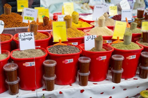 A market stall with red buckets full of colorful spices and Georgian lettering, Akhaltsikhe market,