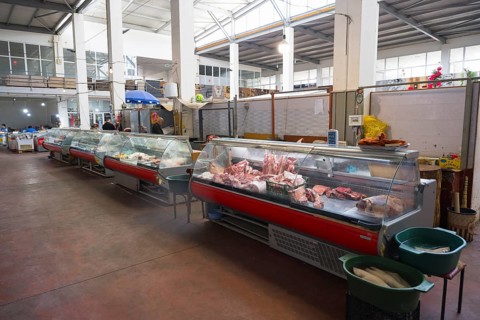 A large market hall with several refrigerated display cases full of meat, Akhaltsikhe market,
