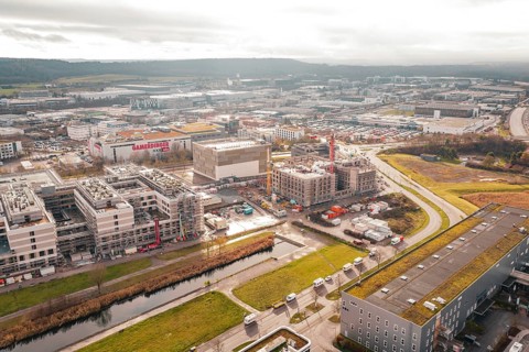 New hospital construction site with buildings and cranes near a river under cloudy sky, Böblingen,