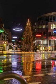 Illuminated Christmas tree and colorful lights in a rainy urban environment at night, Böblingen