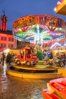 Colourfully lit children's carousel with vehicles at a Christmas market in the evening, Böblingen
