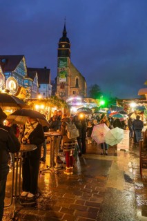 Lively Christmas market in rain with people and illuminated church in the background, Böblingen