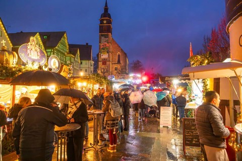 People with umbrellas and festive lighting at a Christmas market at night, Böblingen Christmas