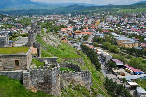 Panorama of a city with historic castle ruins on a hill under cloudy sky, Rabati Fortress,