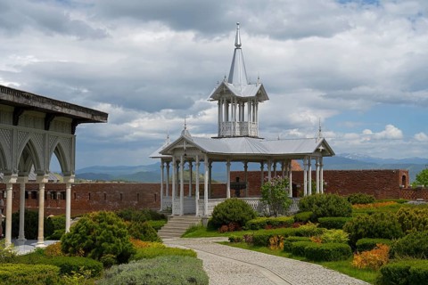 Elegant white pavilion in a well-kept garden with a curved path and mountain views, Rabati