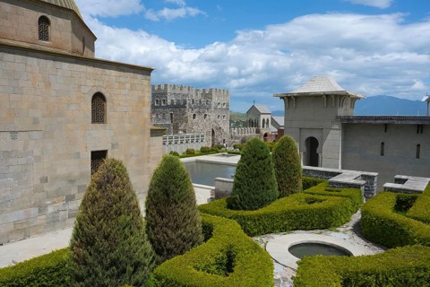 Medieval garden complex with hedges and towers against a clear, slightly cloudy sky, Rabati