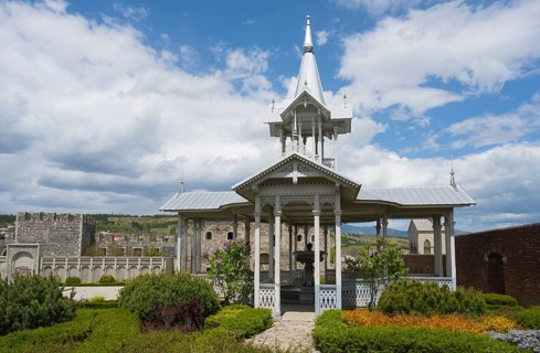 White wooden pavilion in a well-kept garden under a cloudy sky, Rabati Fortress, Akhaltsikhe,