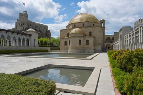 Building ensemble with golden dome, stone arcades and water basin in front of a fortress, Rabati