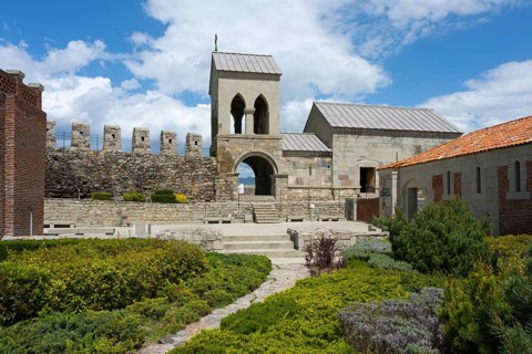 Historic church building with bell tower and adjoining garden under blue sky, Rabati Fortress,