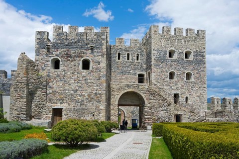 Massive stone fortress with towers and well-kept garden under slightly cloudy sky, Rabati fortress,