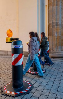 Passers-by at the security barrier made of massive bollards at the Brandenburg Gate passage,