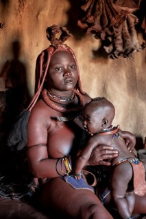 Himba woman sitting with baby in traditional hut, Himba village, Kaokoveld, Kunene, Namibia
