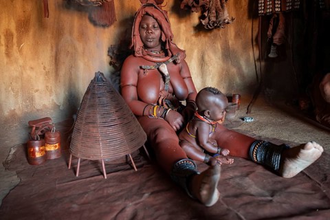 Himba woman sitting with baby, Himba perfume, scented smoke from burning plants, Himba village,