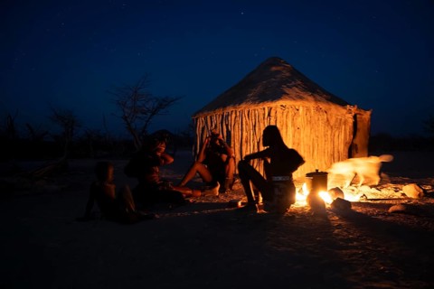 Himba at the campfire in the evening, night view, Himba huts, traditional Himba village in the