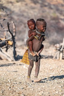 Himba child carrying baby piggyback, traditional Himba village, Kaokoveld, Kunene, Namibia