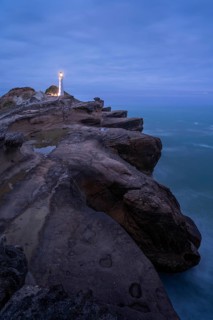 Castlepoint lighthouse on a rock, ocean, evening, blue hour, illuminated, long exposure.