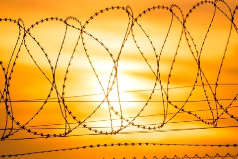 Sun sets behind barbed wire fence, bright orange and yellow tones, Baden-Württemberg, Germany