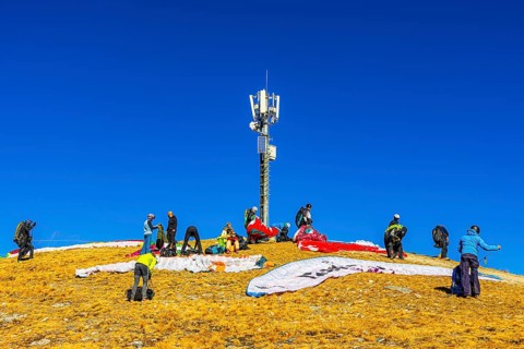 Paragliders prepare for takeoff below the transmitter and cell phone tower, summit of the Corne de