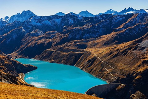 The turquoise Lac de Moiry reservoir with the dam, behind the peaks of the Grand Cornier, Tete