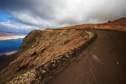 Coastal road along a dramatic cliff under a cloudy sky, Haria Lanzarote, Canary Island