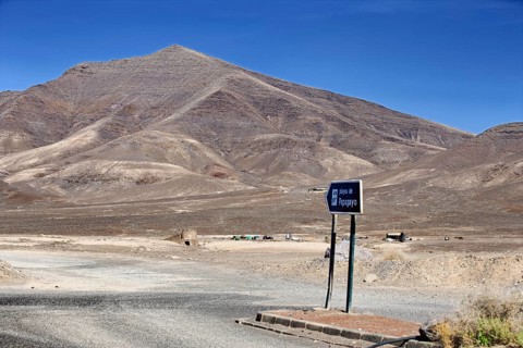 Lonely volcanic landscape with a sign to the beach under clear skies, Playa Blanca Lanzarote,