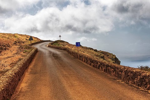 Secluded road along a rocky coast under a cloudy sky, Haria Lanzarote, Canary Island