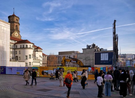 Passers-by, excavator, construction site, construction fence, controversial construction project of