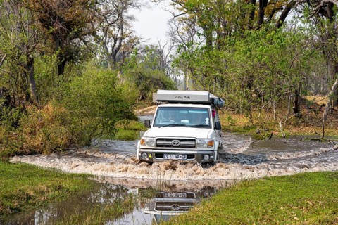 Safari car, off-road car driving through a river, Xakanaxa, Moremi Game Reserve, Botswana
