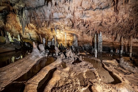 Stalactites and stalagmites, rock formations in a stalactite cave with water basin, Grotta del