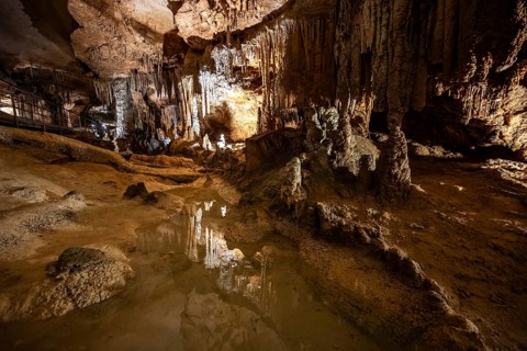 Stalactites and stalagmites, small underground lake, rock formations in a stalactite cave, Grotta