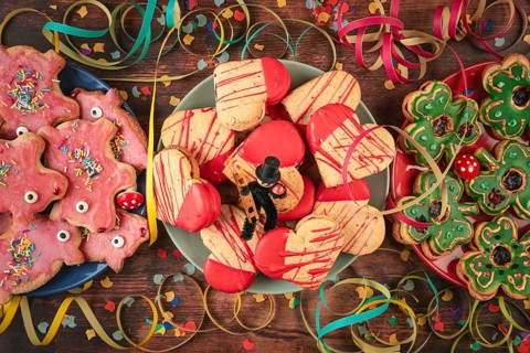 Various colorful cookies on wooden table with confetti, streamers and lucky charms