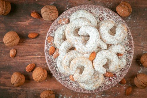 Vanilla croissants on a plate surrounded by walnuts and almonds