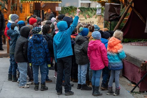 A group of children watches an acrobat on stage, Historischer Christmas market am Neustädter church
