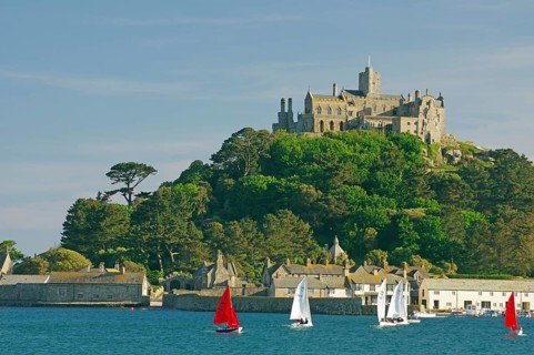 A castle overlooks the sea surrounded by sailing boats and green nature, Penzance, Saint Michael's