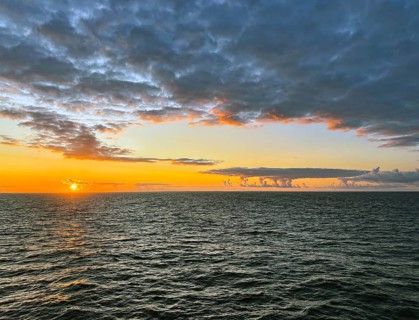 Tranquil ocean horizon at sunset with dramatic clouds and warm hues, Orkney Islands, Scotland,