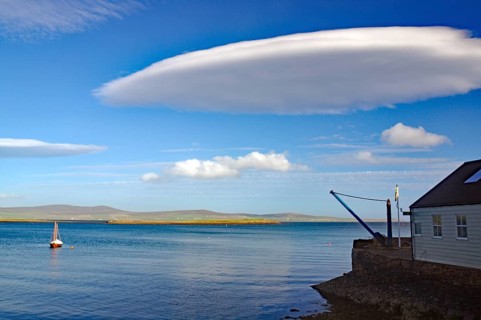 A tranquil ocean view with unique cloud formation and sailboat, UFO clouds, Stromness, Orkney