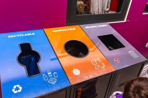 Colorful recycling bins at an airport promoting waste separation into recyclable, compostable, and