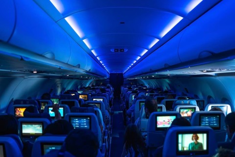 Passengers enjoying in flight entertainment while watching movies on personal screens, surrounded