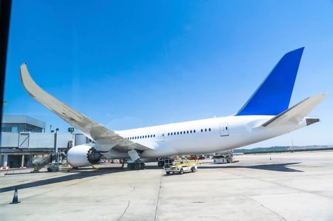 White and blue passenger airplane parked at the airport gate, getting ready for departure under a