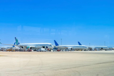 Several airplanes are parked on the tarmac at an airport, waiting for their next flights under a
