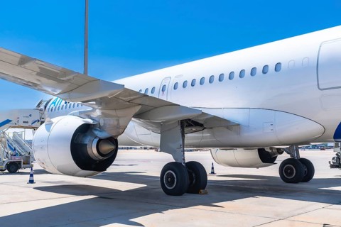 Passenger airplane parked on the airport runway, showcasing its wing, engine, and landing gear,