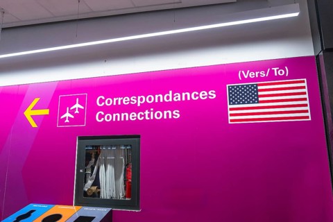 Bright pink airport sign with airplane icons and the flag of the united states of america, guiding