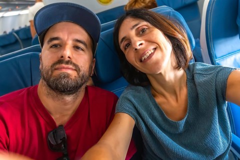Happy couple taking a selfie on an airplane, enjoying their flight while capturing joyful moments