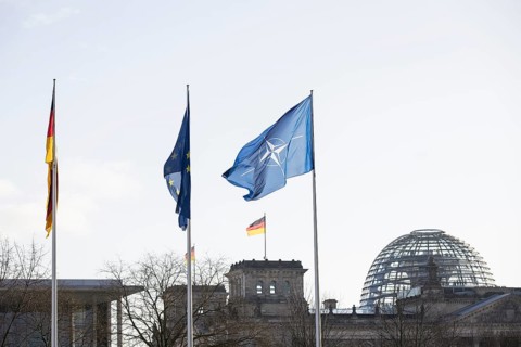 Flags of the Federal Republic of Germany, the EU and NATO in front of the Reichstag building,